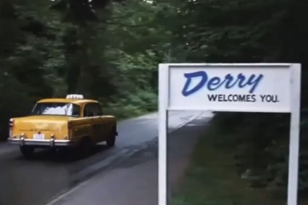 Taxi passing by the Derry welcome sign